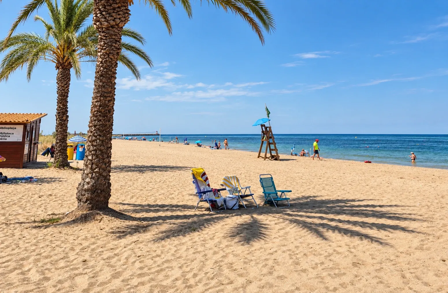 Zandstrand met palmbomen en strandstoelen in Dénia